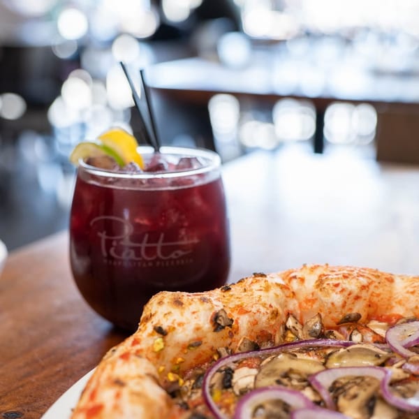 A Piatto Neapolitan Pizzeria branded drink and a pizza with mushrooms and red onions.